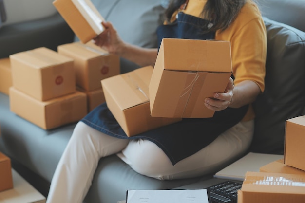 Emprendedores Pequeñas empresas PYME Hombres independientes trabajan en casa Utilizar teléfonos inteligentes y computadoras portátiles para la comprobación comercial en línea marketing cajas de embalaje vendedores PYME concepto de comercio electrónico equipo de ventas en línea