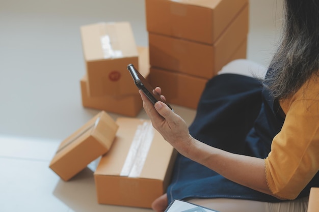 Emprendedores Pequeñas empresas PYME Hombres independientes trabajan en casa Utilizar teléfonos inteligentes y computadoras portátiles para la comprobación comercial en línea marketing cajas de embalaje vendedores PYME concepto de comercio electrónico equipo de ventas en línea