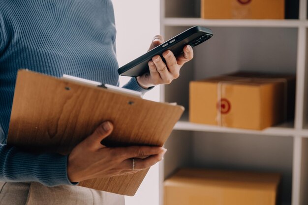 Emprendedores Pequeñas empresas PYME Hombres independientes trabajan en casa Utilizar teléfonos inteligentes y computadoras portátiles para la comprobación comercial en línea marketing cajas de embalaje vendedores PYME concepto de comercio electrónico equipo de ventas en línea