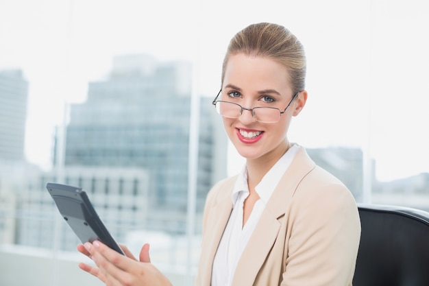Empresária alegre com óculos usando calculadora