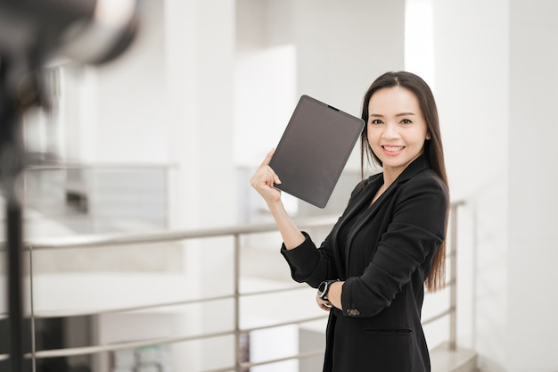 Una empresaria alegre confiada del sudeste asiático profesional en traje de negocios con tableta digital