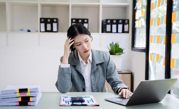 Foto empresaria asiática cansada con dolor de cabeza en la oficina sintiéndose enferma en el trabajo