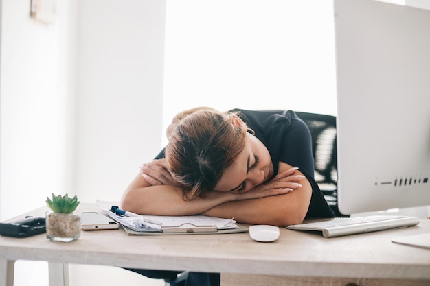 Empresaria asiática cansada y con exceso de trabajo durmiendo en el escritorio en el espacio de trabajo de la oficina