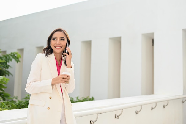 Empresária asiática confiante ao telefone enquanto toma café na pausa para o café