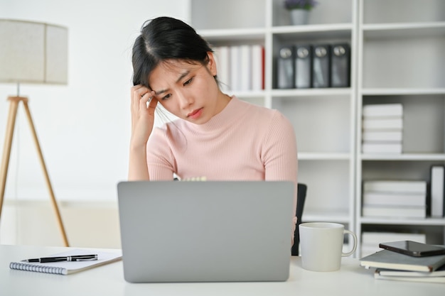 Empresária asiática confusa e estressada olhando para a tela do laptop