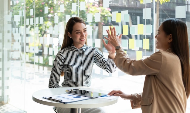 Empresaria asiática dando cinco a un colega en una reunión Profesionales de negocios felices que se reúnen en la sala de conferencias de la oficina