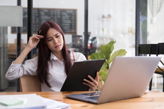 Empresária asiática é séria no trabalho causando dor de cabeça estressada com documentos