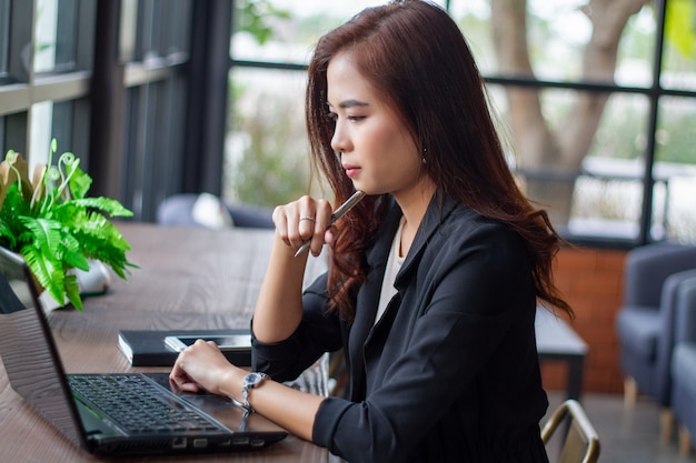 La empresaria asiática está pensando en crear nuevos empleos y está sonriendo y trabajando feliz