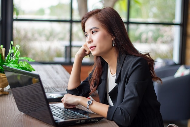 La empresaria asiática está pensando en crear nuevos empleos y está sonriendo y trabajando feliz