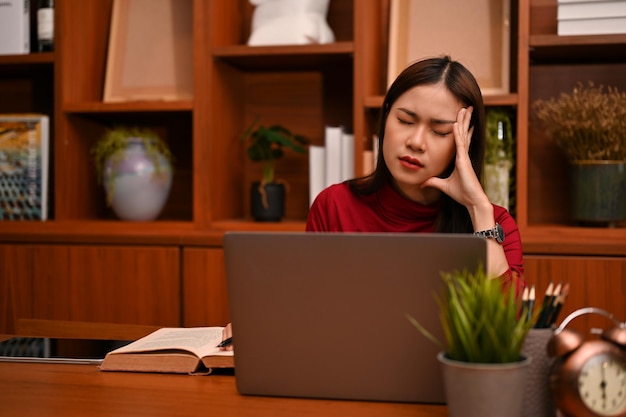 Empresaria asiática estresada y frustrada que sufre de dolor de cabeza