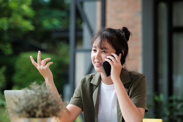 Empresaria asiática joven que trabaja en la oficina usando phonexA móvil