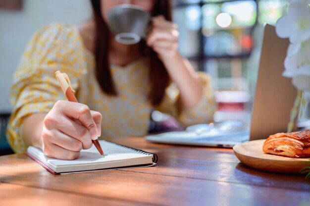 Empresaria asiática en línea trabajando en café. Estilo de vida de la mujer tailandesa con café el fin de semana. Distanciamiento social y nueva normalidad.