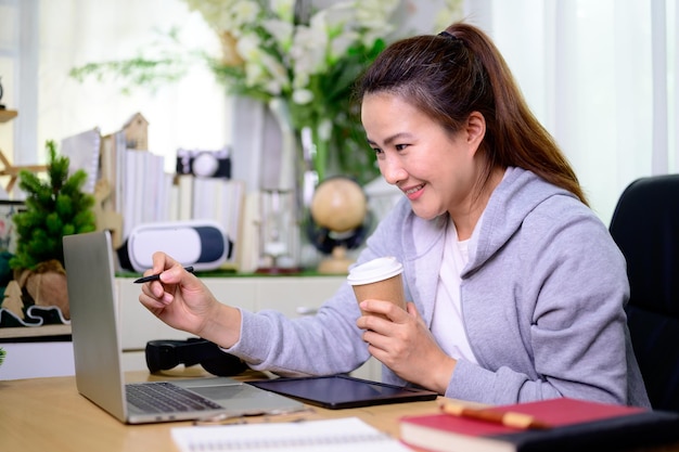 Empresaria asiática en línea trabajando en casa. Estilo de vida de mujer tailandesa en la sala de estar. Distanciamiento social y nueva normalidad.