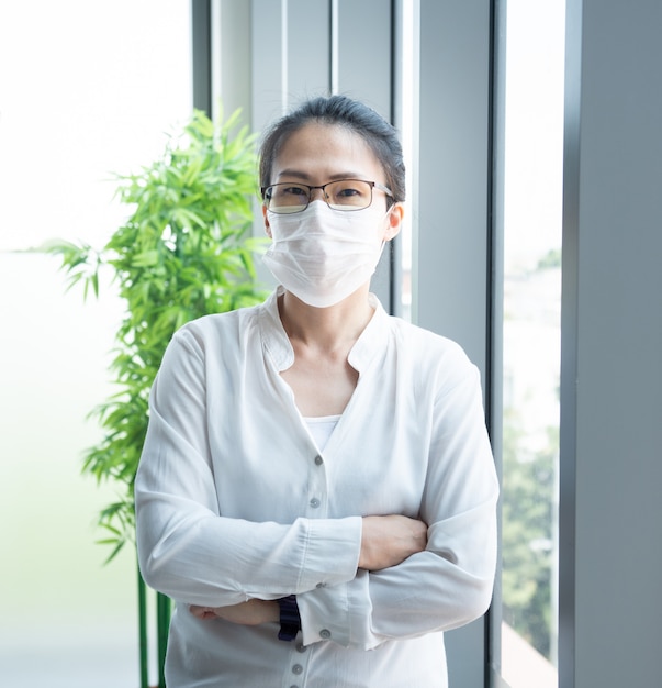 Empresaria asiática con máscara protectora de virus en la oficina