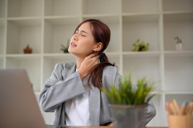 Empresária asiática milenar cansada do trabalho sofrendo de dor no pescoço após o trabalho