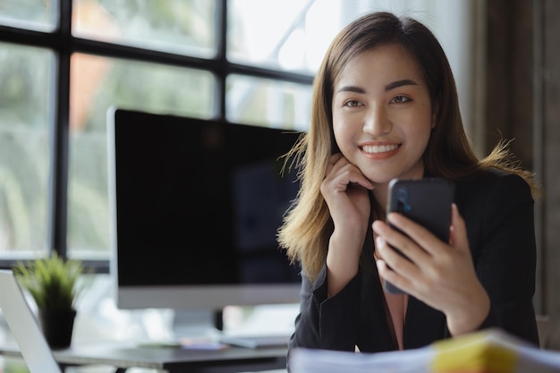 Empresaria asiática mirando la pantalla del teléfono inteligente y la videollamada remota con un socio de inicio que habla con su amiga a través del programa en el concepto de teléfono inteligente de usar tecnología de comunicación