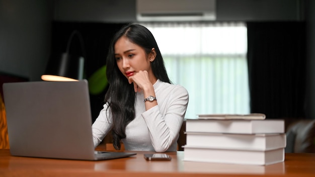 Empresária asiática profissional navegando informações na internet usando laptop