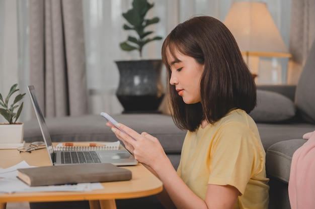 Empresaria asiática que trabaja en línea sola en casa. Estilo de vida de la mujer en la sala de estar. Distanciamiento social y nueva normalidad.