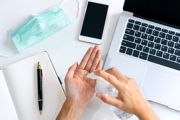 Empresaria asiática que trabaja en el lugar de trabajo y aplica gel desinfectante para manos en la mesa durante la crisis del coronavirus Trabajar desde el hogar y el concepto de atención médica Vista superior