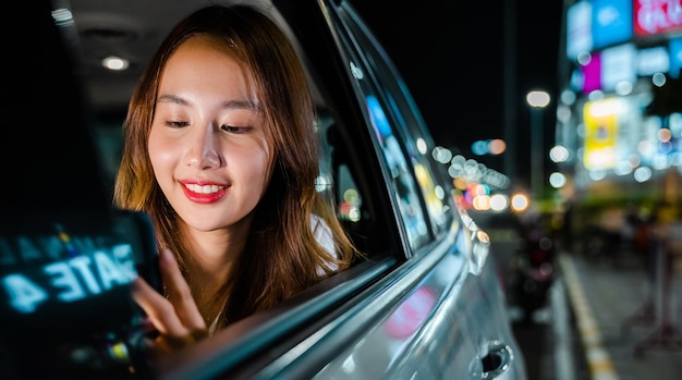 Empresária asiática saindo do escritório no banco de trás do táxi com telefone celular na estrada