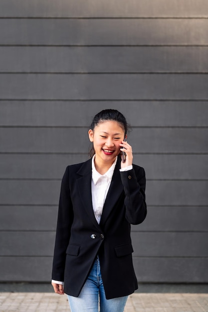 Empresaria asiática sonriente hablando por teléfono