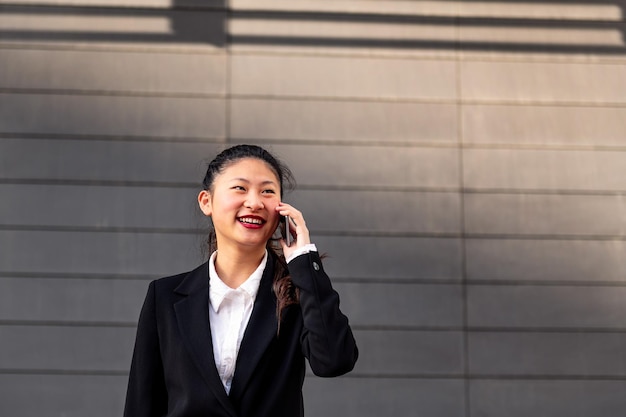 Empresaria asiática sonriente hablando por teléfono