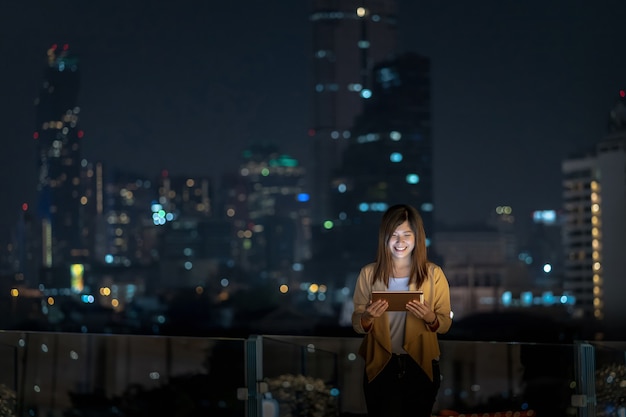 Foto empresaria asiática con tableta con acción de sonrisa en el área del distrito financiero