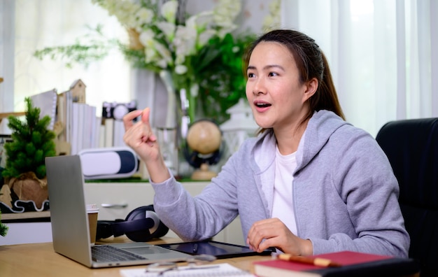 Empresaria asiática trabajando en línea en casa. Estilo de vida de la mujer tailandesa en la sala de estar. Distanciamiento social y nueva normalidad.