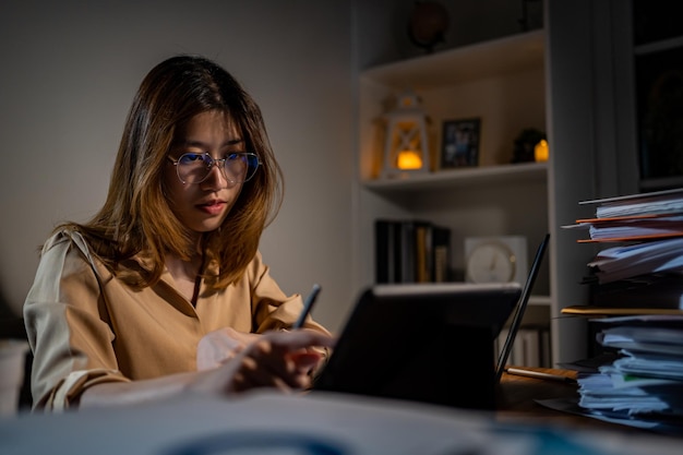 Empresaria asiática trabajando en línea por la noche. Ocupado y agotado de horas extras de trabajo en casa