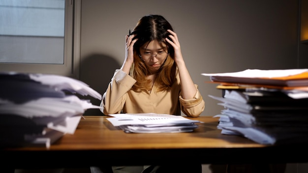 Empresaria asiática trabajando en línea por la noche. Ocupado y agotado de horas extras de trabajo en casa