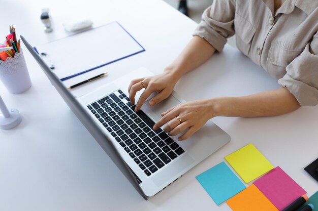 Empresaria asiática trabajando en una oficina creativa. mujer sentada en el escritorio y usando una computadora portátil. distanciamiento social en el lugar de trabajo durante la pandemia de covid 19.