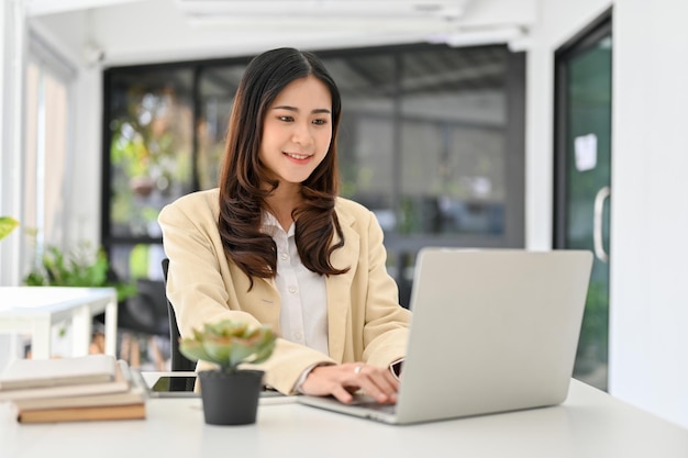 Empresária asiática trabalhando no escritório usando laptop fazendo seus slides de apresentação no laptop