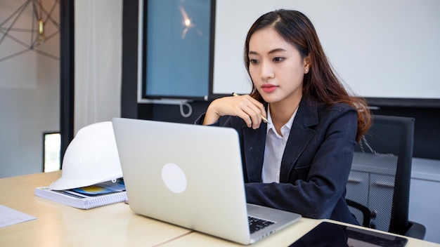 Empresária asiática usando laptop para trabalhar e pesquisando na internet em seu escritório