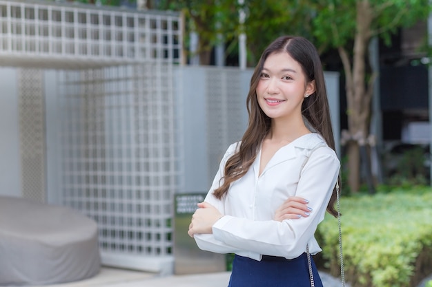 Empresaria asiática vistiendo una camisa blanca y de pie con sus brazos cruzados sonrisa