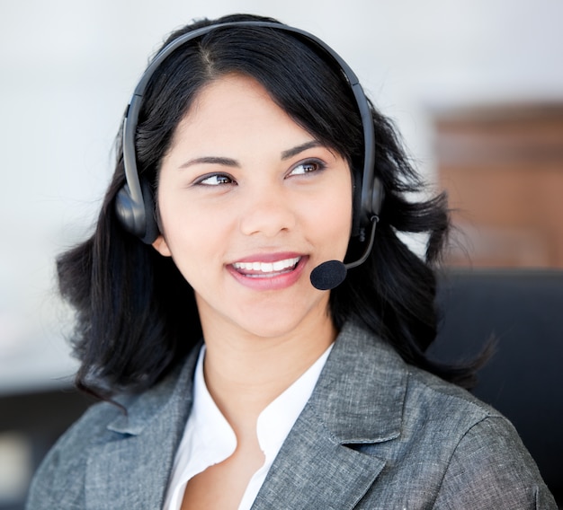 Empresaria atractiva usando un auricular para hablar con los clientes