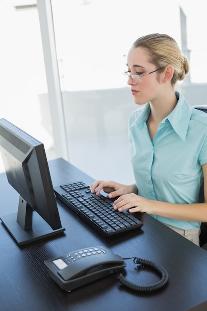 Foto empresaria bastante concentrada sentada en su escritorio trabajando en su computadora