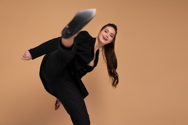 Empresária batendo com a perna na câmera vestida sorriso terno escritório preto isolado na cor de fundo. Lute por negócios. Pose de Karate de arte marcial no estúdio em fundo cinza. estilo kung fu