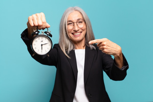 Empresaria bonita mayor con un reloj de alarma. concepto de tiempo