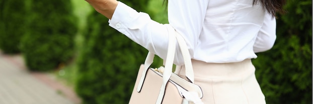 La empresaria camina y sostiene el bolso de cuero beige en su mano. Concepto de estilo de vida moderno y elegante.