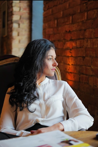 La empresaria con una camisa blanca en el almuerzo en una cafetería o restaurante