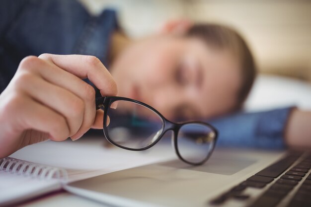 Foto empresária cansada segurando óculos enquanto tirando uma soneca no escritório