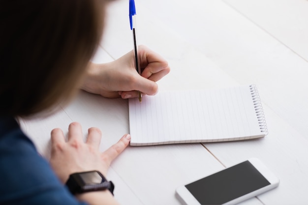 Empresária casual, escrevendo em notebooks em sua mesa com tecnologias