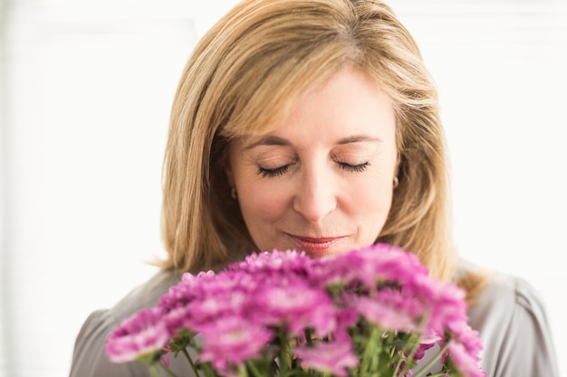 Empresaria casual que huele a flores en la oficina