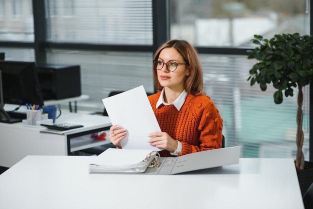 Empresaria casual en suéter sentado en su escritorio en la oficina