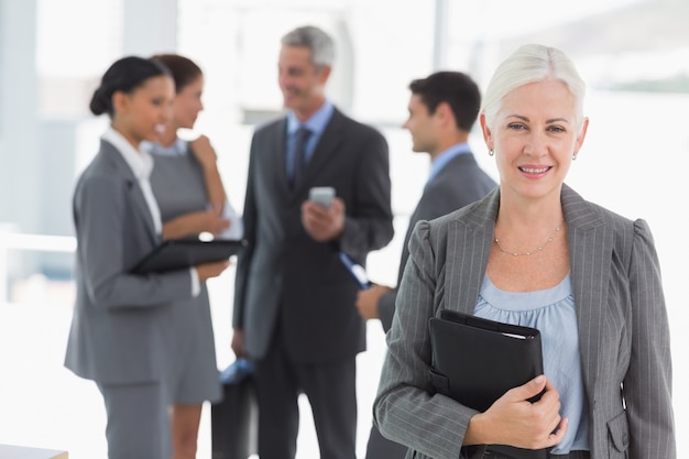 Empresaria con colegas detrás en la oficina