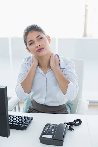 Empresária com dor no pescoço na frente do computador