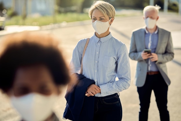 Foto empresária com máscara facial esperando na fila a uma distância segura durante a epidemia de coronavírus