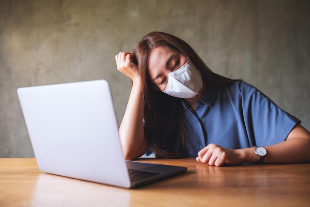 Empresária com máscara facial protetora fica estressada enquanto trabalha no laptop no escritório