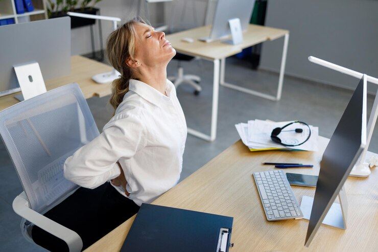 Foto empresária de meia idade tendo dor nas costas enquanto está sentado na mesa de escritório