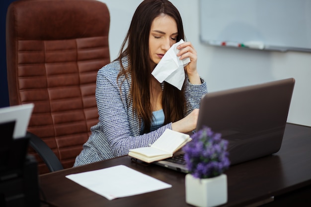 Empresária desesperada on-line preocupada após a falência na frente de um laptop com as mãos na cabeça no escritório